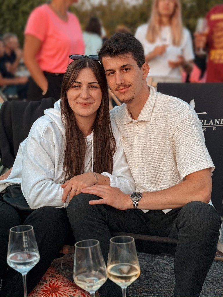 Lena und Bastian sitzen zusammen bei einem Abend im Freien
